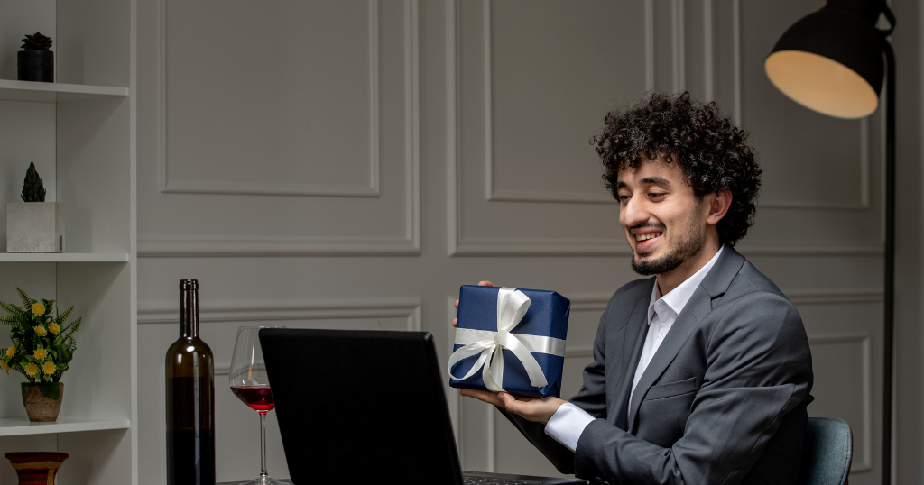 A businessman in a suit, smiling while holding a wrapped luxury corporate gift during a virtual meeting, symbolizing high-end gifting in Dubai.