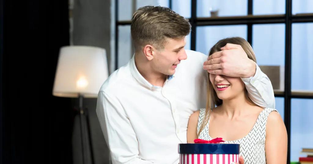 A romantic moment as a man surprises his partner with a gift, symbolizing love and anniversary celebration.